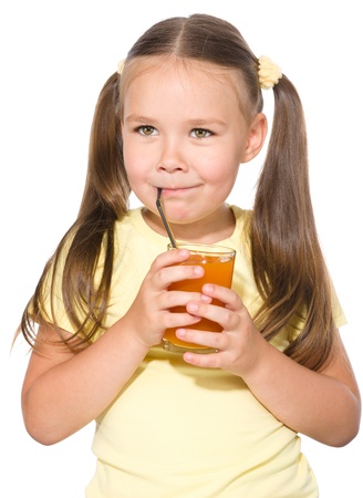 Little girl is drinking carrot juice using straw, isolated over whiteの写真素材