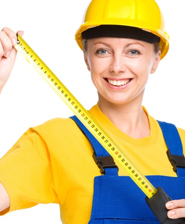 Young happy lady as a construction worker with tape measure, isolated over whiteの写真素材