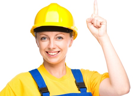 Young happy lady as a construction worker is pointing up with her forefinger, isolated over whiteの写真素材