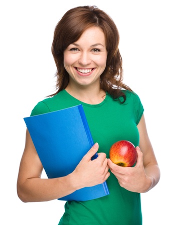 Young skinny student girl is holding exercise book and apple, isolated over whiteの写真素材