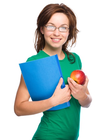 Young skinny student girl is holding exercise book and apple, isolated over whiteの写真素材