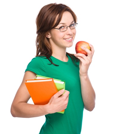 Young skinny student girl is holding exercise book and apple, isolated over whiteの写真素材