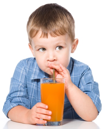 Little boy is drinking carrot juice using straw, isolated over whiteの写真素材