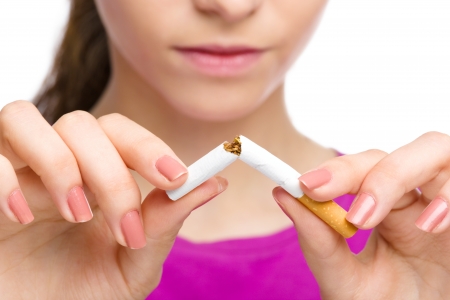 Young woman is breaking a cigarette, quit smoking concept, isolated over white