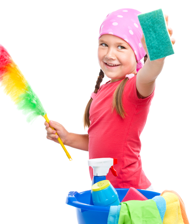 Young girl is dressed as a cleaning maid, holding static duster and sponge, isolated over whiteの写真素材