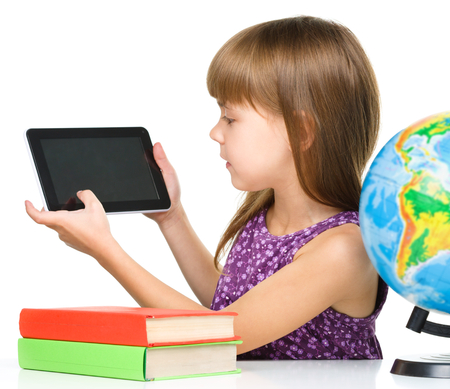 Young girl is showing tablet while sitting at table, isolated over whiteの写真素材
