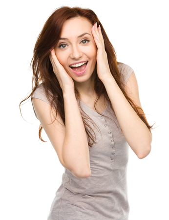 Young woman is holding her face in astonishment, isolated over whiteの写真素材