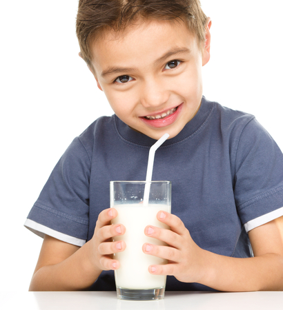 Cute boy drinks milk using a drinking straw, isolated over whiteの写真素材