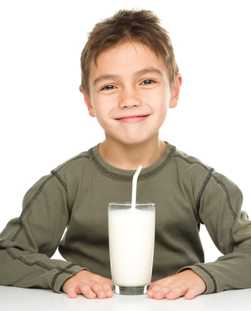 Cute boy drinks milk using a drinking straw, isolated over whiteの写真素材