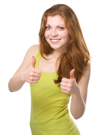 Young woman is showing thumb up gesture using both hands, isolated over whiteの写真素材