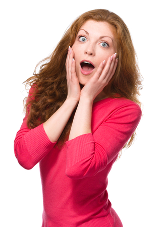 Young woman is holding her face in astonishment, isolated over whiteの写真素材