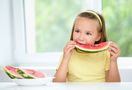 Cute little girl is eating watermelon, isolated over whiteの写真素材