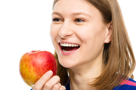 Young happy girl is holding red apple, isolated over whiteの写真素材
