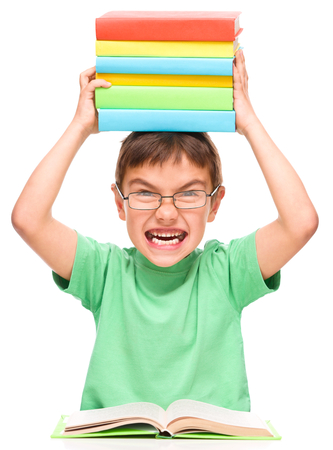 Little boy is holding a pile of books and showing aggressive grimace, isolated over whiteの写真素材