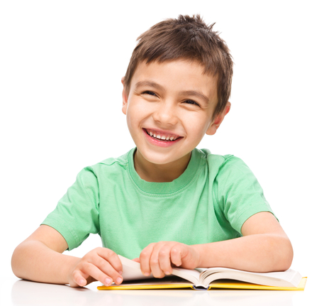 Cute little boy is reading a book, isolated over whiteの写真素材