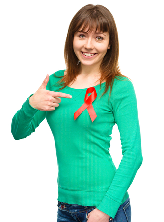 Woman is pointing to the red awareness ribbon, isolated over whiteの写真素材
