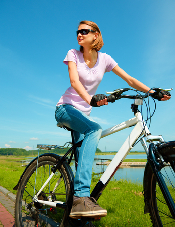 Young happy woman is sitting on her bicycle, outdoor shootの写真素材