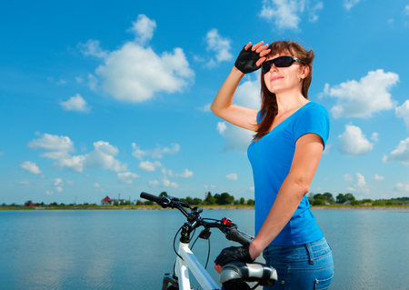 Young woman is standing behind of her bicycle, outdoor shootの写真素材