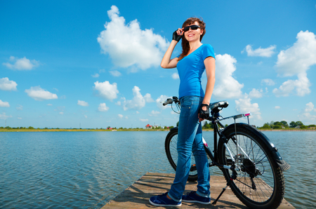 Young woman is standing in front of her bicycle, outdoor shootの写真素材