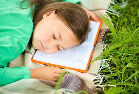 Little girl is sleeping on her book outdoorsの写真素材