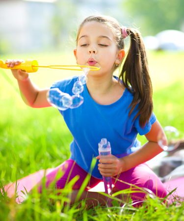 Cute little girl is blowing a soap bubblesの写真素材