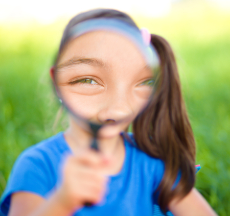 Little girl is looking through magnifier, outdoor shootの写真素材