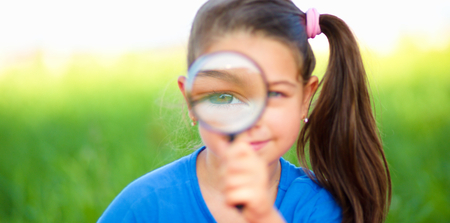 Little girl is looking through magnifier, outdoor shootの写真素材