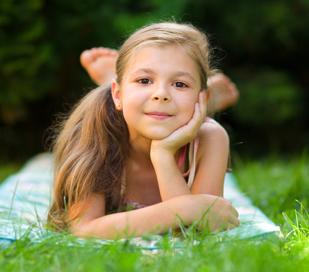 Portrait of a little girl laying on green grass, outdoor shootの写真素材