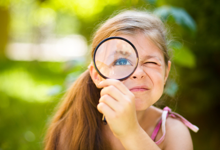 Little girl is looking through magnifier, outdoor shootの写真素材