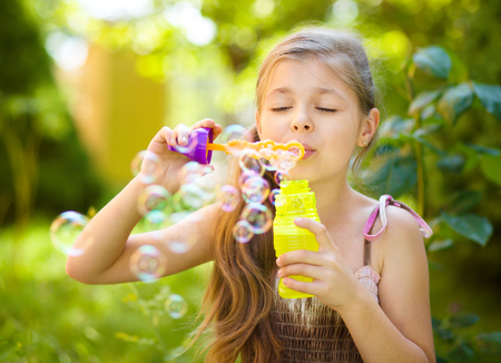 Cute little girl is blowing a soap bubbles, outdoor shootの写真素材