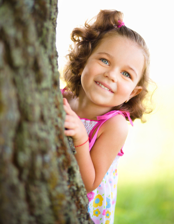 Cute little girl is playing hide and seek, outdoor shootの写真素材