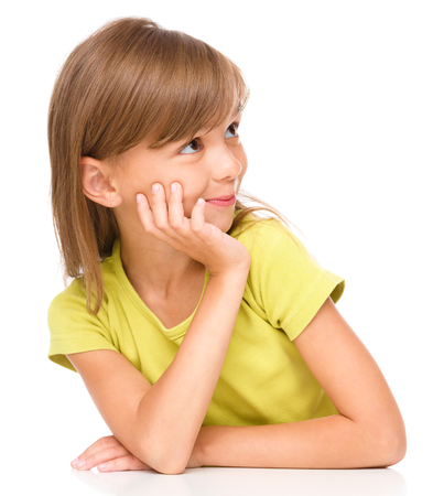 Portrait of a pensive little girl supporting her head with hand and looking to the right, isolated over whiteの写真素材