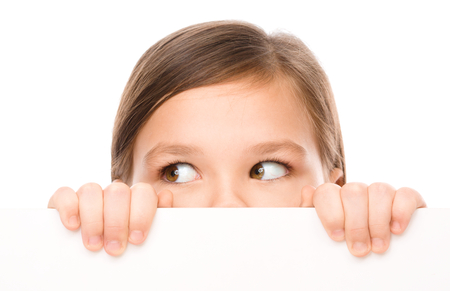 Little girl is looking from out blank board, isolated over whiteの写真素材