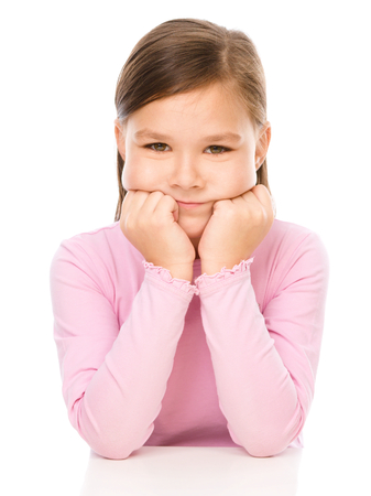 Portrait of a sad little girl supporting her head with hands, isolated over whiteの写真素材