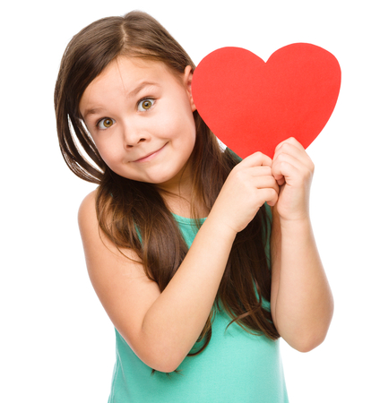 Portrait of a little girl holding red heart, isolated over whiteの写真素材