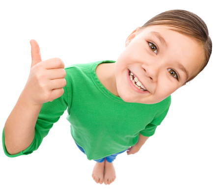 Little girl is showing thumb up gesture, fisheye portrait, isolated over whiteの写真素材
