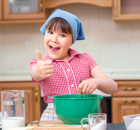 Girl is cooking in kitchen and showing thumb up sign, indoor shootの写真素材