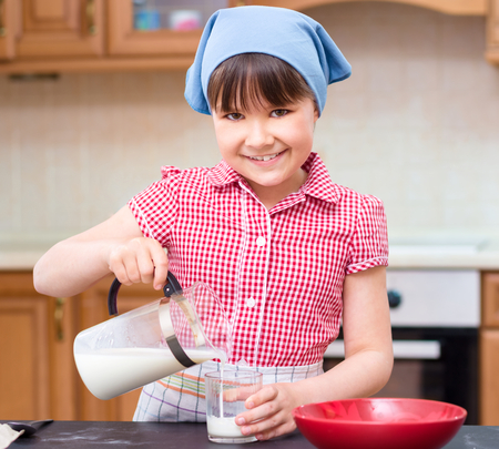 Girl is cooking, pouring milk in glass, indoor shootの写真素材