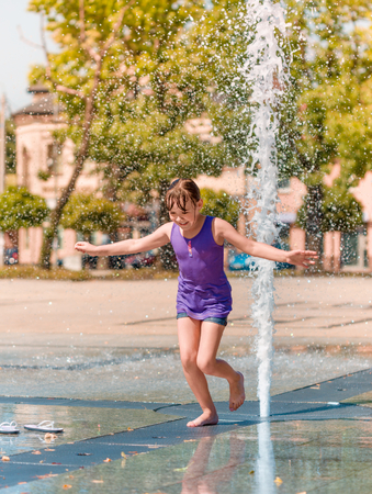 Hot summer in the city - girl is enjoying fountain with cold waterの写真素材