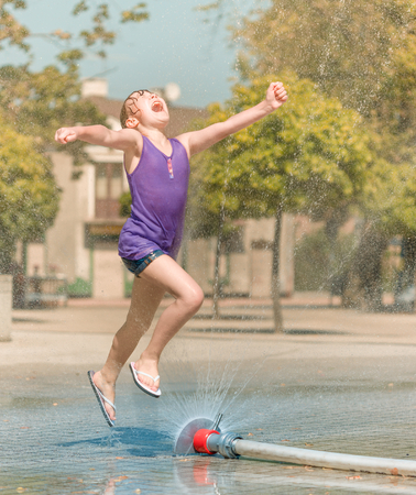 Hot summer in the city - girl is running through fountainsの写真素材
