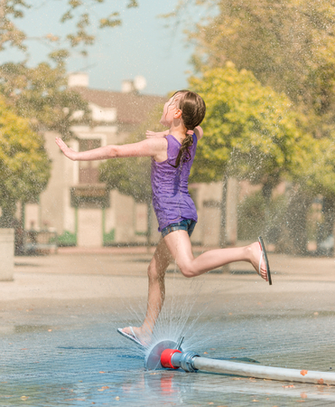 Hot summer in the city - girl is running through fountainsの写真素材