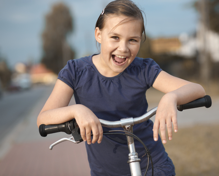 Cute girl is sitting on bicycle, outdoor portraitの写真素材