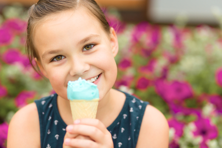 Little girl is eating ice-cream in park, outdoor shootの写真素材