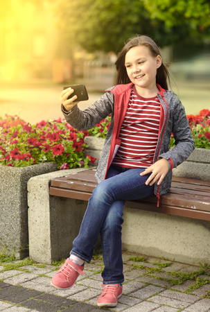 Girl is making photo using a phone, outdoor shootの写真素材