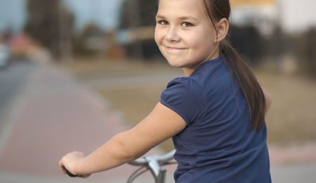 Cute girl is sitting on bicycle, outdoor portraitの写真素材