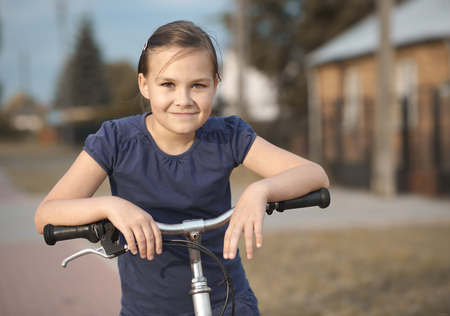 Cute girl is sitting on bicycle, outdoor portraitの写真素材