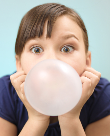 Little girl is blowing big bubble gum, closeup portraitの写真素材