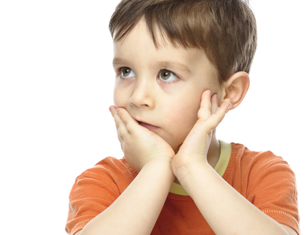 Portrait of a cute little boy sitting at table supporting his head with hand, isolated over whiteの写真素材
