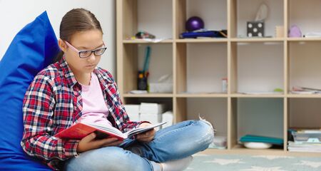 Girl is reading book while sitting in room, indoor shoot