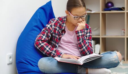 Girl is reading book while sitting in room, indoor shoot